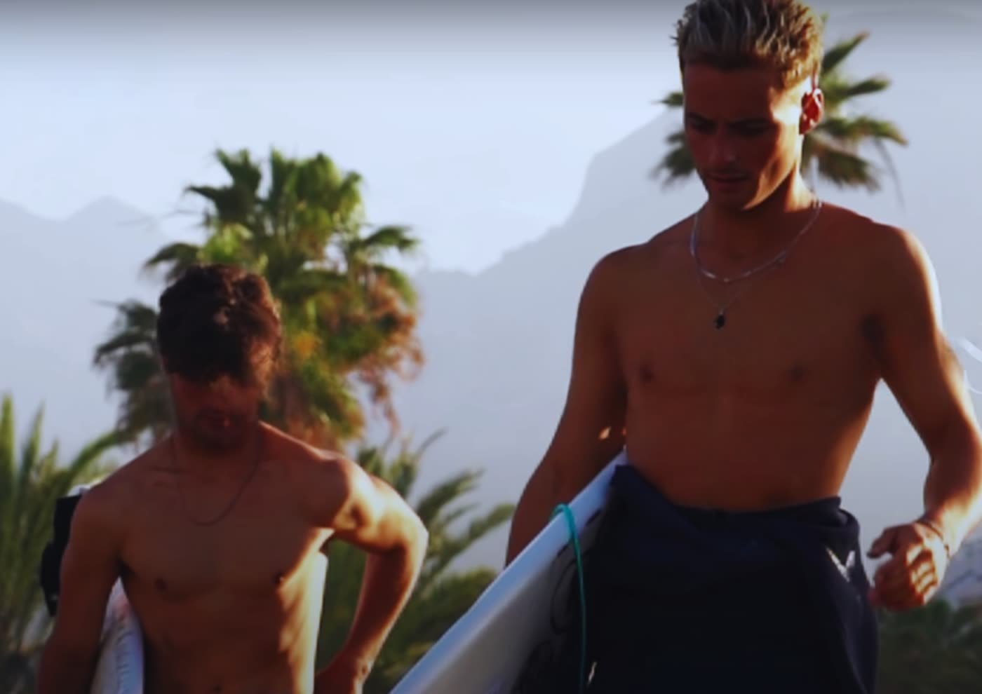 Javi y Álvaro saliendo del agua con sus tablas al atardecer